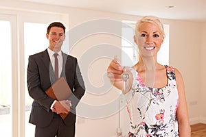 Estate Agent Handing Over Keys Of New Home To Female Buyer