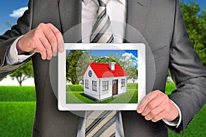 Estate agent showing photo with house on tablet