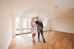 Estate Agent Showing Young Woman Around New Empty Property