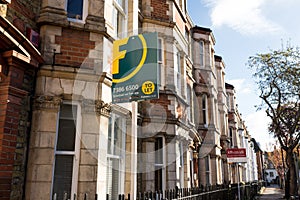 Estate agent signs outside a row of Victorian terraced houses