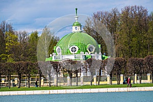 Evening view through the palace pond on the park pavilion `Grotto` in museum-estate Kuskovo, Moscow.