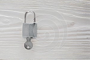 Estate concept with symbol of security, lock padlock with key on wooden background.