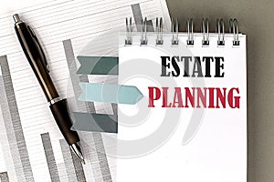 ESTATE PLANNING text on notebook with pen, calculator and chart on a grey background