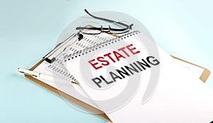 ESTATE PLANNING text on notepad on clipboard with chart on blue background, concept closeup. Business and finance concept