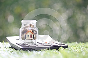 Estate tax,Model house and gold coin money in the glass bottle with calculator on natural green background,Business investment and