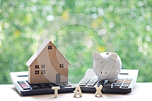 Estate tax,Model house and piggy bank on calculator with on natural green background,Business investment and Property tax concept