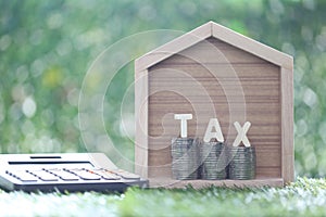 Estate tax,Model house with stack of coins money and tax word on  green background,Business investment and Property tax concept