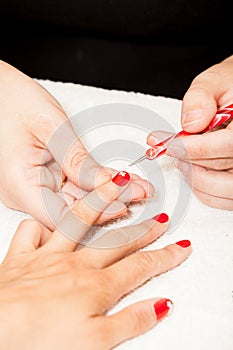 The esthetician decorates with flowers the nails of the hands of the client