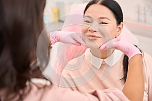 Esthetician doctor analyzes the patients skin turgor