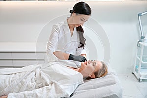 Esthetician makes beauty injections to a beautiful blonde woman