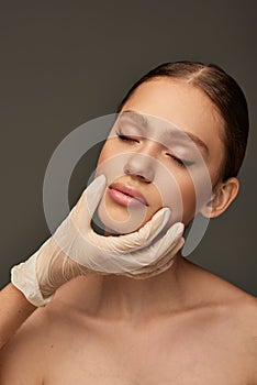 esthetician in medical glove touching face