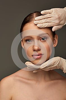 esthetician in medical gloves touching face