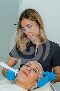 esthetician performs relaxing treatment on the cheekbone of a woman