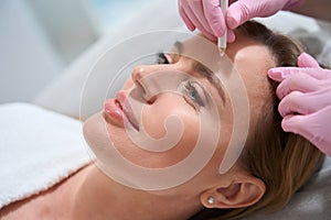 Esthetician uses a special marker to mark the working areas