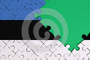 Estonia flag is depicted on a completed jigsaw puzzle with free green copy space on the right side