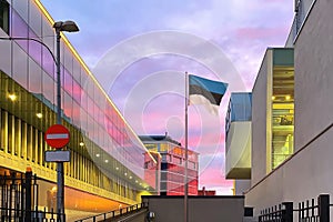 Estonia  Flag Symbol in Tallinn  on   pink sunset clouds blue sky  in the windows of modern buildings city architecture urban life