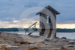 Estonia, on the island of Hiiumaa, next to a rocky pier, there is a small wooden house rising above the water