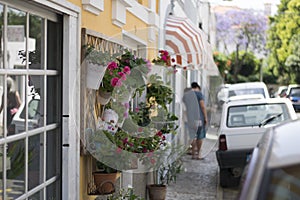 Estoril little street on summer time, colorful flowers in pots on the wall