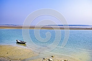 Estuary, mouth of a river, outlet with a boat at the east cost India at the Sunrise in a clear morning Spring time.