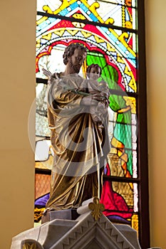 Esus Christ statue with stained glass window in the background