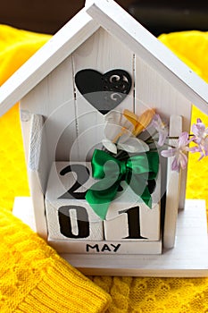 An eternal calendar in the form of a house on a spring yellow background.