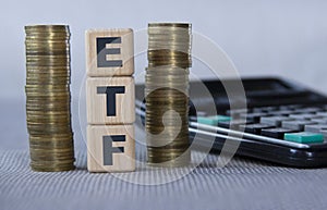 ETF - acronym on wooden cubes on the background of coins and calculator