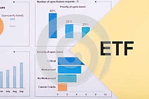 ETF. Exchance Traded Fund. Text on yellow paper on financial charts. Business concept