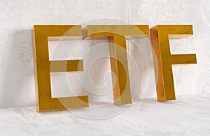 ETF - exchange traded funds - acronym in golden letters leaning against concrete wall on white wooden floor background