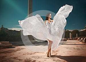 Ethereal, divine bride with flying, shiny dress standing in temp