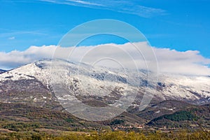 Ethereal Majesty: Snow-Drifted Peaks Amidst Passing Clouds