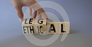 Ethical and Legal symbol. Businessman hand turnes wooden cubes and changes word Ethical to Legal. Beautiful grey background.