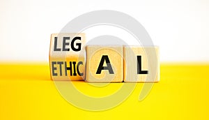 Ethical or legal symbol. Businessman turns wooden cubes and changes the word Ethical to Legal on a Beautiful yellow table white