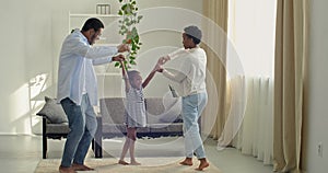 Ethnic african american family young couple mom and father parent spend time with girl child dancing with daughter in