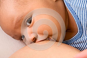 Ethnic baby boy enjoying regular breastfeeding