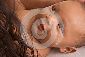 Ethnic biracial baby boy lying down by mother