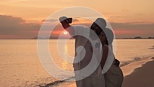 Ethnic couples taking selfies in the setting sun on the beach at sunset, Africans American and Asian, romantic atmosphere