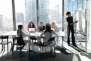 Ethnic female coach make flip chart presentation at meeting