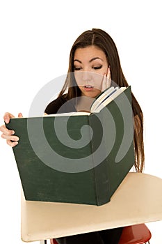 Ethnic girl sitting at school desk reading a book