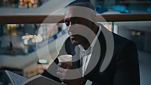 Ethnic male African man businessman employer entrepreneur drinking tea aromatic hot coffee at table in cafe cafeteria