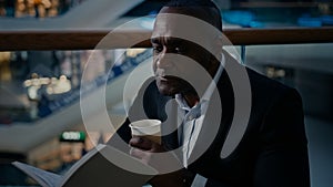 Ethnic male African man businessman employer entrepreneur drinking tea aromatic hot coffee at table in cafe cafeteria