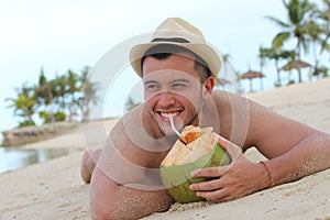 Ethnic male drinking a fresh coconut at the beach