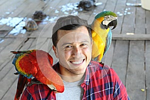 Ethnic man interacting with two gorgeous macaws