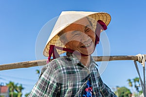 Ethnic old woman in straw hat in a garden in village near Hoi An city, Vietnam