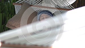 Ethnic woman with turban napping take rest on hammock during day time relax lifestyle