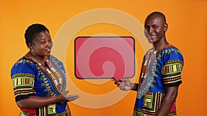 Ethnic young couple presenting speech bubble board