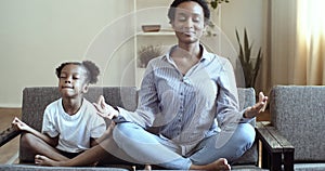 Ethnicity family mindful african mom teaching cute black kid daughter doing yoga exercise at home, calm healthy mixed