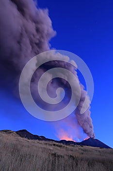 Eruzione Etna durante vista all'alba con grandi emissioni di cenere dal cratere della cima del vulcano nel cielo azzurro