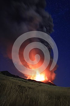 L\'Etna in Sicilia grande eruzione con grandi emissioni di cenere dal cratere del vulcano nel ciel notturno stellato photo