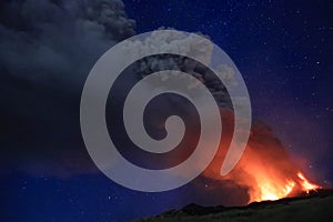 L\'Etna in Sicilia grande eruzione con grandi emissioni di cenere dal cratere del vulcano nel ciel notturno stellato photo