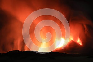 Etna durante suggestiva eruzione di notte con grandi emissioni di vapore nel cielo notturno dal cratere della cima del vulcano del photo